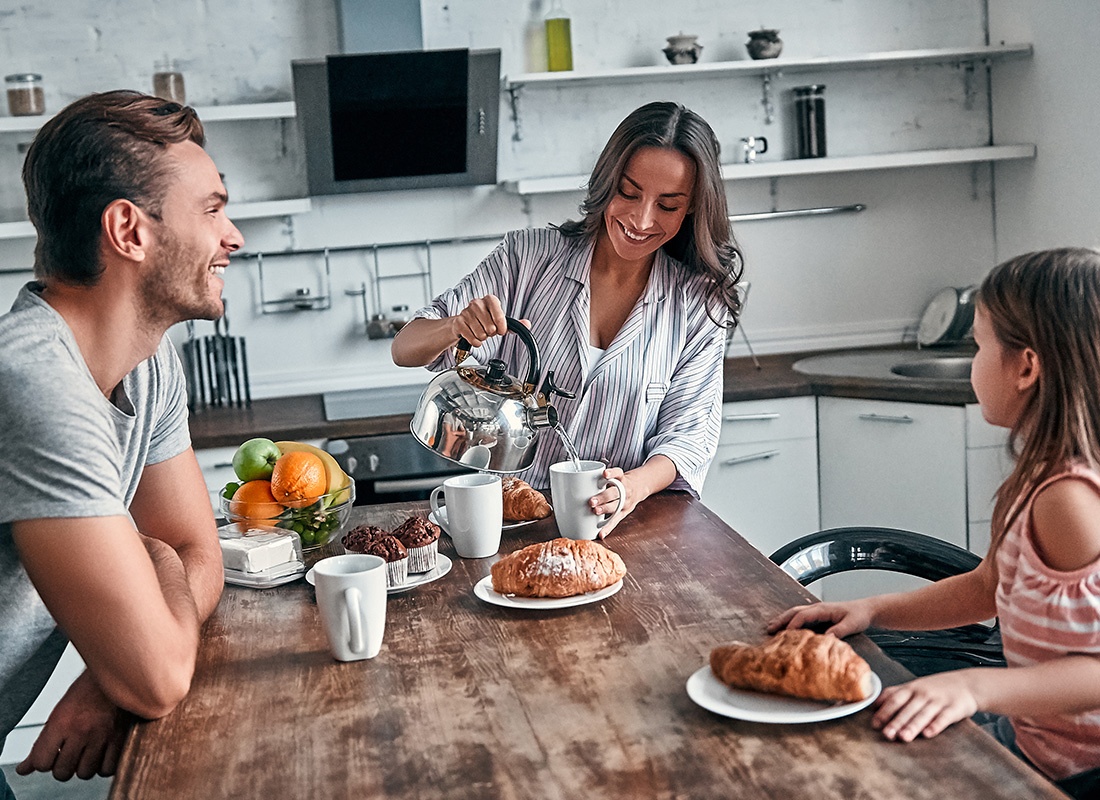 Insurance Solutions - Happy Family Sitting Together at Home Having Breakfast